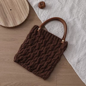 Detailed view of the brown knit handbag featuring premium round wooden handles and texture