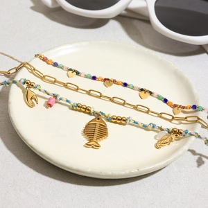 Three-piece gold-tone layered bracelet set with colorful beads and ocean-themed charms