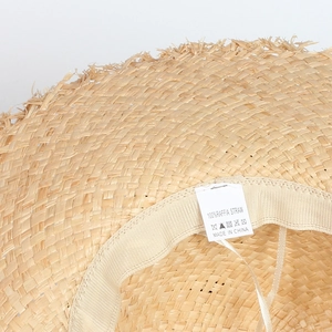 Détail d'un chapeau en paille de raphia montrant la texture et l'étiquette de matière