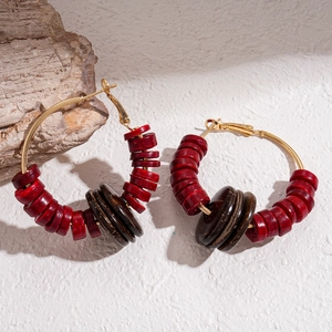 Detail of bohemian hoop earrings with red and brown coconut shell beads on gold hooks