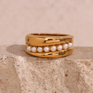 Detailed close-up of wide 18K gold plated ring with white pearls on natural stone