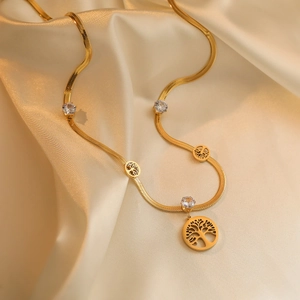 Gold tree of life pendant necklace with zircon crystals on champagne silk background