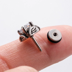 Close-up of retro stainless steel ear stud with zircon inlay and screw-back detail