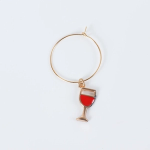 Detail of a golden alloy earring charm featuring a red wine glass shaped pendant drop