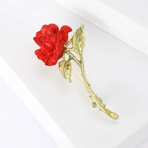 Macro shot of elegant red enamel rose brooch with detailed golden metal stem and thorns