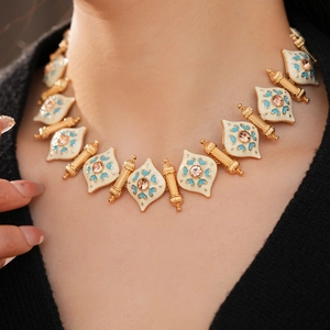 Detail of vintage gold necklace with blue floral enamel and pink rhinestone centerpiece