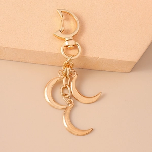 Golden crescent moon keychain with star charms and D-ring on soft neutral background