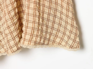 Close-up of checkered dress hem featuring seersucker fabric and delicate lace trim