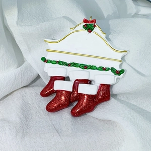 Detail of resin fireplace Christmas ornament with three red glitter stockings and holly leaf decor