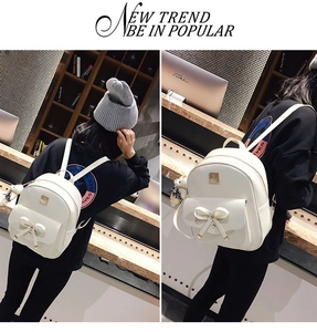 Detailed view of white backpack with bow decoration and cute plush bear charm