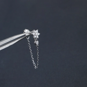Macro shot of silver flower stud earring with long chain tassel and sparkling crystals