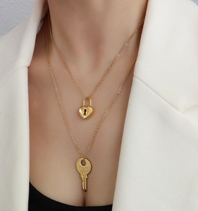 Close-up of double-layer gold lock and key pendant necklace set on a female model