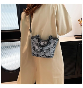 Detail of vintage style handbag with intricate black and white embroidery and leather strap