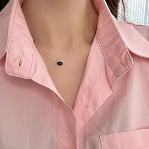 Detail of elegant black oval onyx pendant on a slim silver chain worn by a model