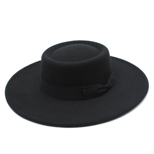 Detail of a black wool felt flat brim boater hat with a chic matching silk ribbon bow