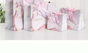 Macro detail of marble pattern gift bags with pink ribbon handles in four sizes