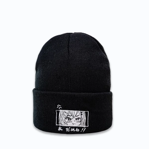 Détail du bonnet en tricot noir avec broderie d'yeux d'anime et texte japonais