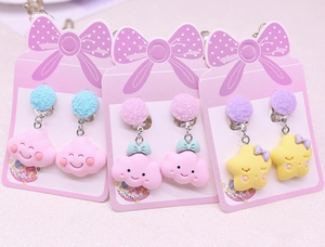 Detail of three pairs of kids' clip-on earrings with colorful pom poms and cute charms