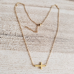 Detailed close-up of a gold stainless steel horizontal cross pendant on a thin link chain