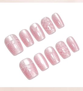 Detail of pink cat-eye press-on nails with 3D bows, butterfly motifs and grid patterns
