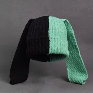Detail shot of the two-tone knit beanie featuring long bunny ears in black and mint green