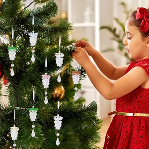 Little girl hanging crystal acrylic pine cone ornaments on a Christmas tree