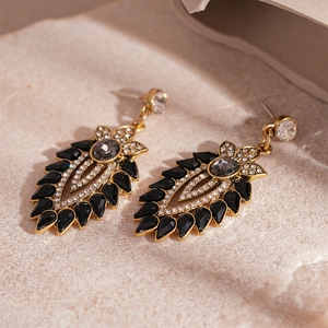 Close-up of vintage gold leaf earrings featuring black gemstones and clear crystals