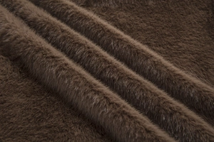 Detailed macro view of dark brown faux fur fabric with dense long pile and glossy texture