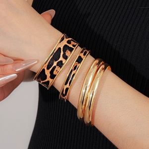 Gros plan d'un ensemble de bracelets empilables léopard et dorés au poignet féminin