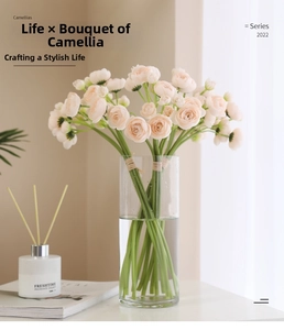 Close-up of light pink artificial camellia bouquet in a clear glass vase for home decor