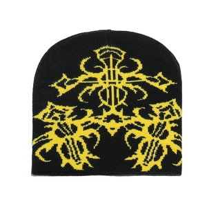 Dettaglio del berretto in maglia nera con motivo totem astratto giallo in jacquard