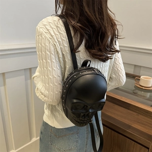Unique 3D skull shaped black backpack with stud accents worn by model in a stylish setting