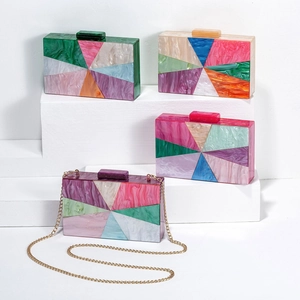 Macro view of geometric acrylic evening clutch with marble texture and gold chain