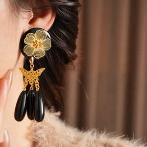 Detail of vintage flower butterfly earrings with black teardrop tassels on model