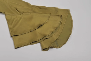 Dettaglio dell'abito in raso verde oliva con eleganti maniche e orlo a balze a strati