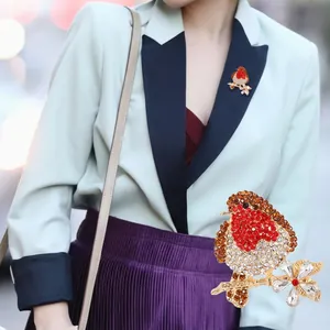 Detail shot of vintage robin bird brooch with red crystals and golden alloy setting