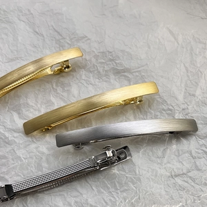 Macro detail of matte brushed metal hair clips in gold and silver finish with spring closure