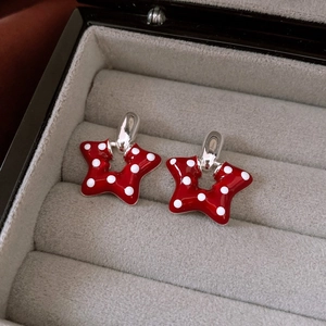 Macro view of red star-shaped earrings with white polka dots on grey velvet