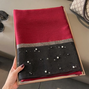 Detail of red and black silk scarf featuring elegant pearl beads and golden trim accents
