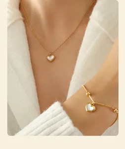 Close-up of heart-shaped shell pendant necklace and bracelet set in gold finish