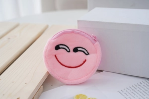 Close-up of pink plush coin purse featuring an embroidered smile and top zipper detail