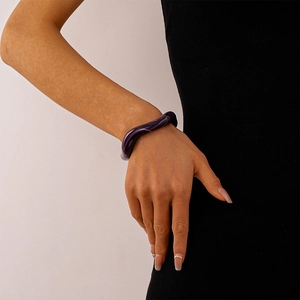 Close-up of a deep purple wavy acrylic resin bangle with marble texture on woman wrist