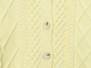 Detail of soft yellow cable-knit cardigan featuring marble texture buttons and intricate weaving