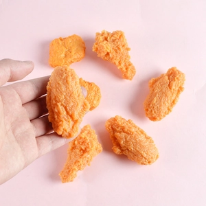 Detailed view of realistic PVC fried chicken models with crispy skin textures on pink background
