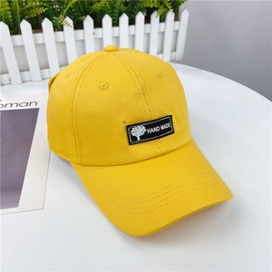 Detail of yellow cotton twill baseball cap with hand made woven label on white surface
