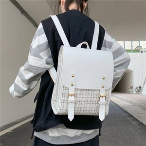 Detail of white straw woven backpack featuring smooth leather flap and gold metal buckles