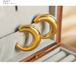 Macro shot of 18K gold plated chunky C-shaped hoop earrings on grey velvet lining
