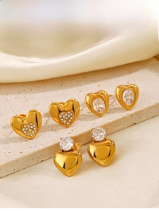 Dettaglio macro di tre orecchini a cuore placcati oro 18K con zirconi su base in pietra