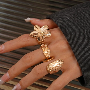 Detailed view of three gold rings with flower shapes and irregular lava textures on fingers