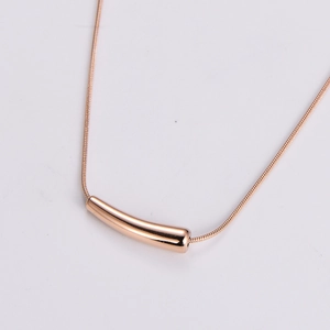 Macro detail of rose gold snake chain necklace with sleek curved bar pendant
